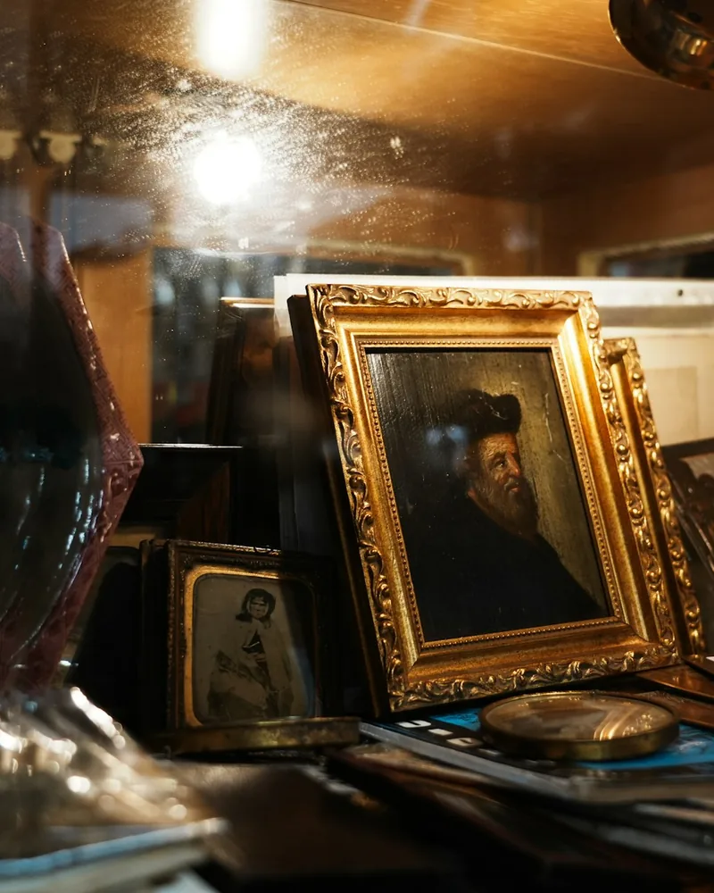 Marco dorado con talla ornamental sosteniendo un retrato antiguo, junto a otros marcos apilados