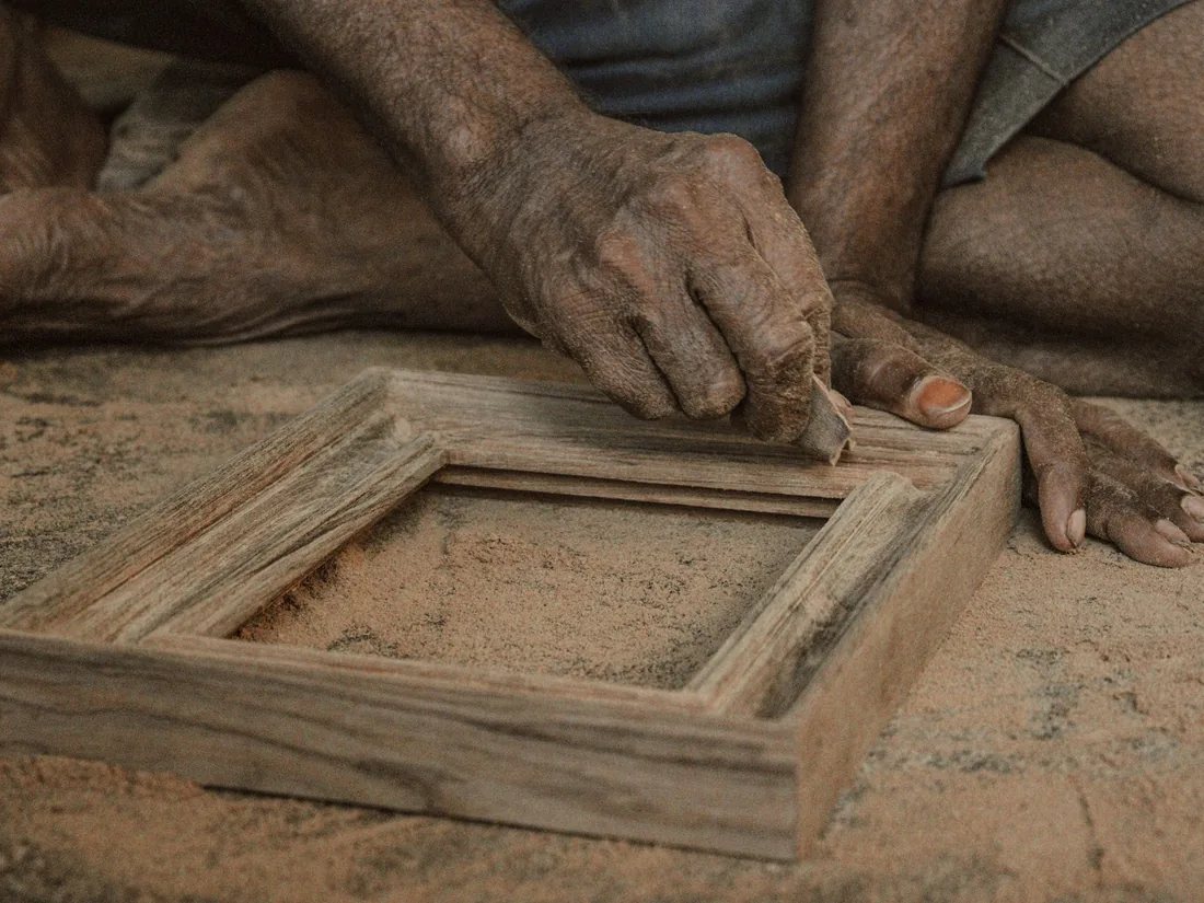 Manos ajustando a mano la esquina de un marco de madera sin acabar